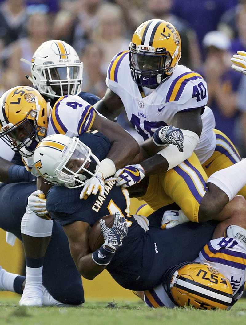 Chattanooga running back Darrell Bridges (14) is tackled by LSU linebacker K'Lavon Chaisson (4), linebacker Devin White (40), and defensive end Christian LaCouture, bottom, during the first half of an NCAA college football game in Baton Rouge, La., Saturday, Sept. 9, 2017. (AP Photo/Rusty Costanza)