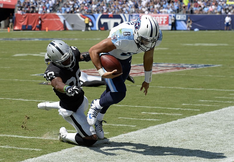 Tennessee Titans quarterback Marcus Mariota is pushed out of bounds by Oakland Raiders cornerback T.J. Carrie during Sunday's game in Nashville. The Raiders won 26-16 in the season opener for both teams.