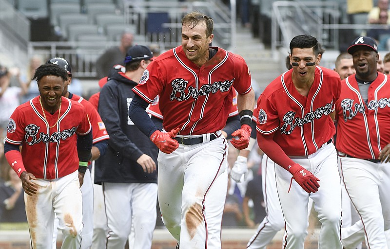 Atlanta Braves' Lane Adams, center, runs out of a mob at home plate after hitting a two-run home run to end the 11th inning of a baseball game against the Miami Marlins, Sunday, Sept. 10, 2017, in Atlanta. (AP Photo/John Amis)