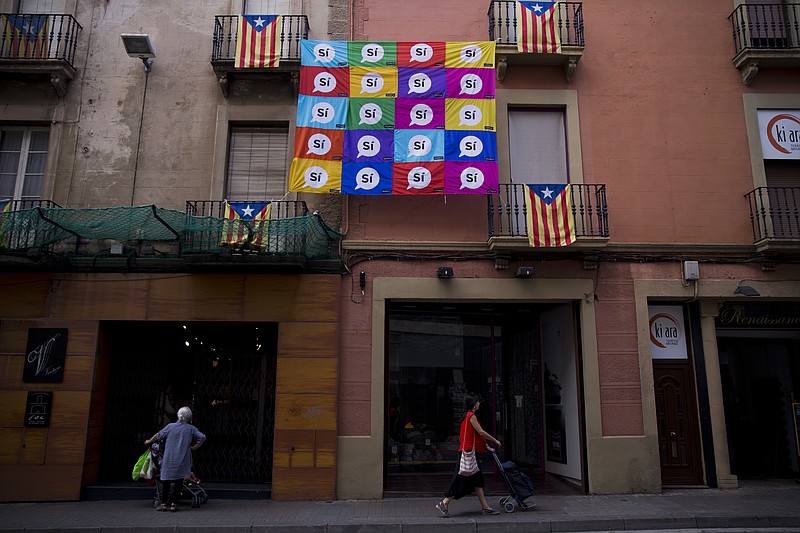 
              People walk on a street decorated with a banner calling to vote Yes in the independence referendum and "esteladas" or independence flags in Sabadell, near Barcelona, Spain, Thursday, Sept. 7, 2017. Spanish Prime Minister Mariano Rajoy's office says members of his cabinet are meeting Thursday to react to plans by Catalan leaders who have scheduled a vote on the region's secession from Spain. (AP Photo/Emilio Morenatti)
            