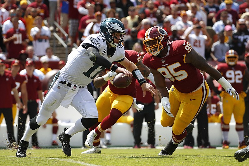 
              Philadelphia Eagles quarterback Carson Wentz, left, tries to outrun Washington Redskins defensive end Jonathan Allen (95) and outside linebacker Preston Smith as he looks for a receiver in the first half of an NFL football game, Sunday, Sept. 10, 2017, in Landover, Md. (AP Photo/Alex Brandon)
            