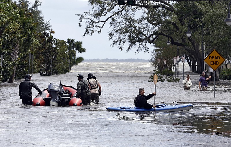 Rescue workers, left, search a neighborhood for flood victims as a man on a kayak down the street after Hurricane Irma brought floodwaters to Jacksonville, Fla. Monday, Sept. 11, 2017. (AP Photo/John Raoux)