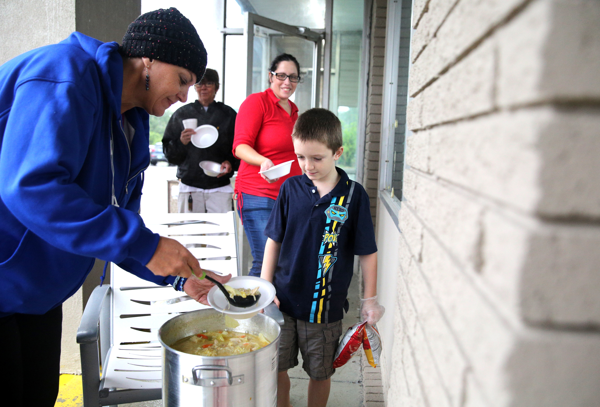 Deb Jones, Kingsland, Ga., scoops out a bowl of soup she prepared for Brave Benson, 9, as Rose Benson of Hudson, Fla., and Martha Johnson of Belle Glade, Fla., wait in line Monday, Sept. 11, 2017, at the Budgetel Inn in East Ridge, Tenn. Jones and her husband spent several hours outside making the soup for guests to give back to others that were helping her.