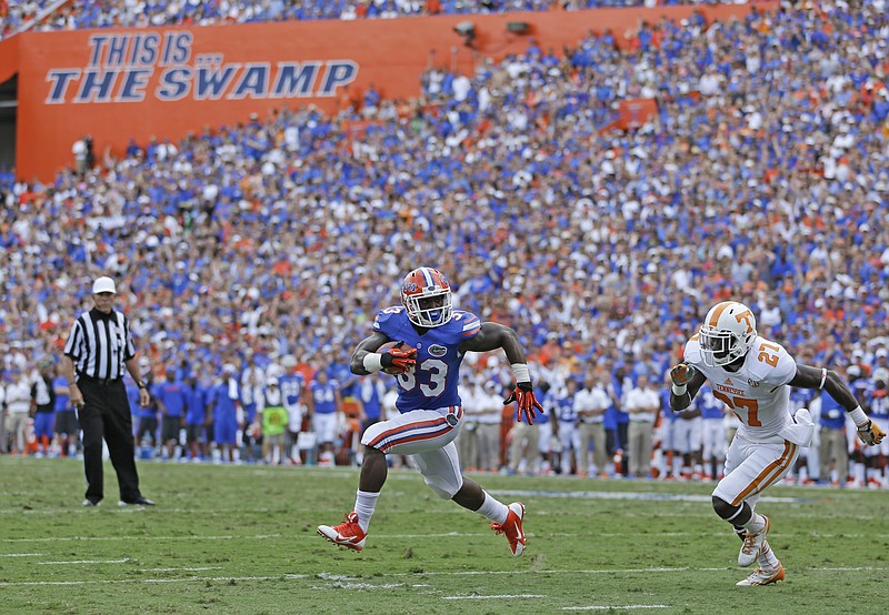 
              FILE - In this Sept. 21, 2013, file photo, then-Florida running back Mack Brown (33) runs a 3-yard touchdown past Tennessee defensive back Justin Coleman (27) during the first half of an NCAA college football game in Gainesville, Fla. After inspecting the stadium, meeting with campus and city officials, and assessing available resources, Florida decided its Southeastern Conference opener against Tennessee would be played as scheduled. So it’s game on in Gainesville. The SEC announced Tuesday, Sept. 12, 2017, that the league opener between the No. 23 Volunteers (2-0) and the 24th-ranked Gators (0-1) will remain a 3:30 p.m. kickoff at Florida Field on Saturday, Sept. 16, 2017, keeping the game intact less than a week after Hurricane Irma devastated parts of the Sunshine State. (AP Photo/John Raoux, File)
            
