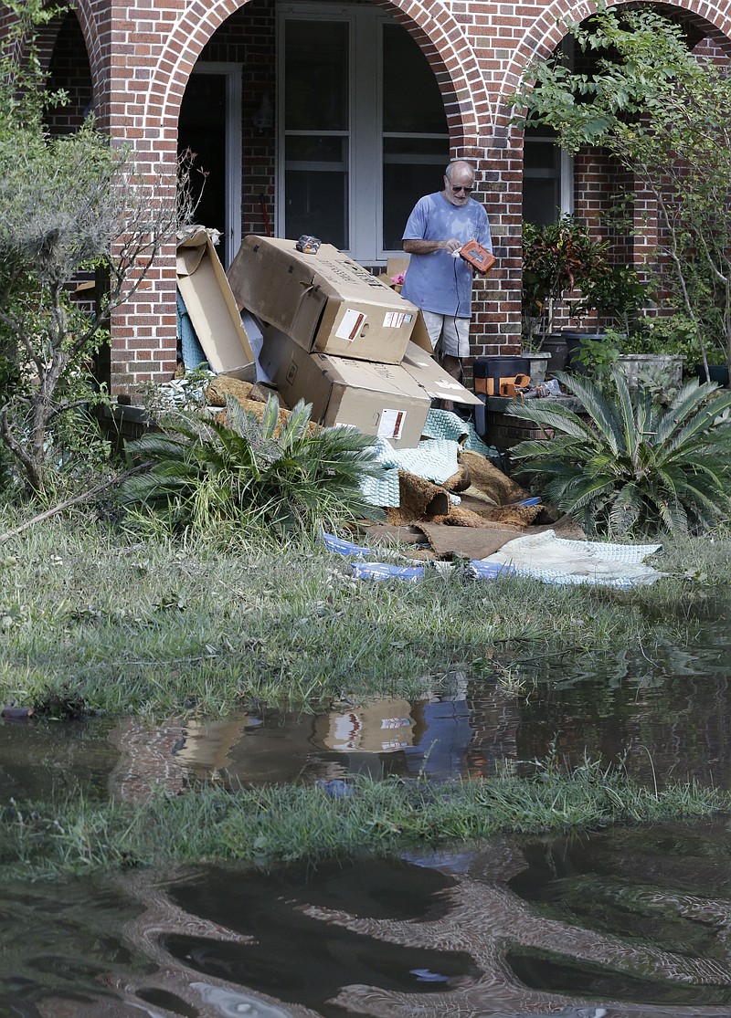 
              A home owner removes water logged items from his home as floodwaters fill the street in the San Marco area of Jacksonville, Fla. in the aftermath of Hurricane Irma, Tuesday, Sept. 12, 2017. (AP Photo/John Raoux)
            