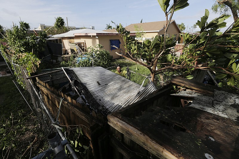 
              Bayardo Perez prepares to dismantle the mangled tin roof of his shed in Sweetwater, Fla., Monday, Sept. 11. Inland communities like Sweetwater were spared the storm surge from Hurricane Irma, but streets were swamped, fences and trees fell, cars got stuck in floodwater, and the ground will remain saturated as trillions of gallons of ocean water flow south through the Everglades. (AP Photo/Jason Dearen)
            