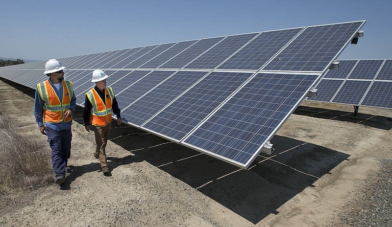 
              FILE - In this Thursday, Aug. 17, 2017, file photo, solar tech Joshua Valdez, left, and senior plant manager Tim Wisdom walk past solar panels at a Pacific Gas and Electric Solar Plant, in Dixon, Calif. Higher energy costs led to prices at the wholesale level rising in August 2017 at the fastest pace in four months, according to information released Wednesday, Sept. 13, 2017, by the Labor Department. (AP Photo/Rich Pedroncelli, File)
            