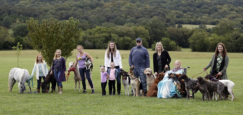 Stephanie Clegg Troxell, right, and her family pose at the acreage where their animals are being kept Tuesday, Sept. 12, 2017, in Bradyville, Tenn. The family evacuated New Port Richey, Fla., before Hurricane Irma hit. The family caravan includes three cars and a trailer, five adults, five children, 13 dogs, three mini-horses and a pet pig. From left are Lily Troxell, 10; Emma Troxell, 13; McKendree Troxell, 14; Harper Clegg, 3; Jacki Clegg; McKaela Clegg, 4; Ted J. Clegg; Lou Clegg; Rose Barbasso, 88; and Stephanie Clegg Troxell. (AP Photo/Mark Humphrey)