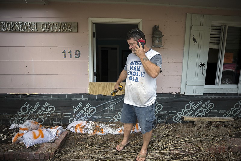 Joey Spalding talks with friends on his cellphone, Tuesday, Sept., 12, 2017, on Tybee Island, Ga., while cleaning up after Tropical Storm Irma flooded his neighborhood yesterday. (AP Photo/Stephen B. Morton)