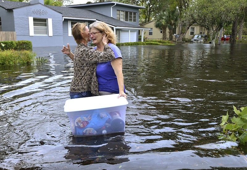 
              Charlotte Glaze gives Donna Lamb a teary hug as she floats out some of her belongings in floodwaters from the Ortega River in Jacksonville, Fla., Monday, Sept. 11, 2017, after Hurricane Irma passed through the area. "This neighborhood has not flooded in at least 51 years," Lamb said. (Dede Smith/The Florida Times-Union via AP)
            