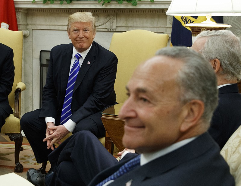 President Donald Trump, left, and Senate Minority Leader Chuck Schumer, D-N.Y., right, smirk as they discuss the president working with Democrats on various legislation recently in the White House Oval Office.