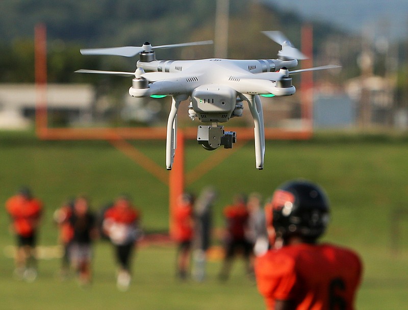 A drone, guided by Devin Parker, foreground, flies toward players during a football practice at South Pittsburg High School last month. Pirates coaches give Parker several drills on which to focus on recording of during practices.