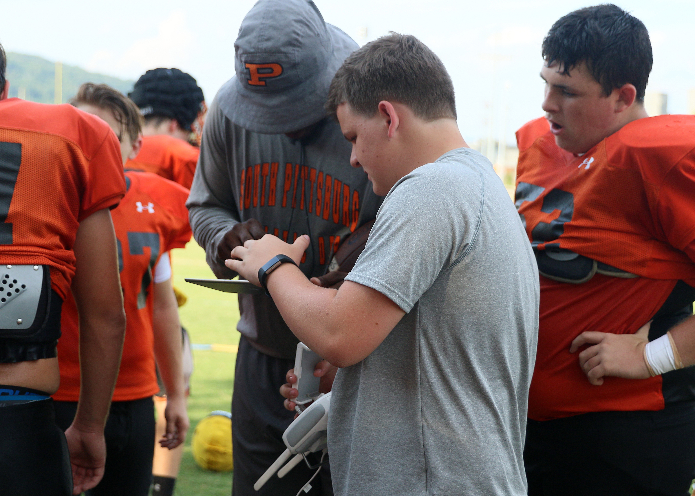 Jiajuan Fennell, a defensive end coach, gets Devin Parker to show him drone footage from practice as Miles Walters looks on Tuesday, Aug. 29, 2017, at South Pittsburg High School in South Pittsburg, Tenn. Parker was offered the task of videoing the football team at practices and games, and he plans on continuing to fly the drone for the football team for the remainder of his high school experience.