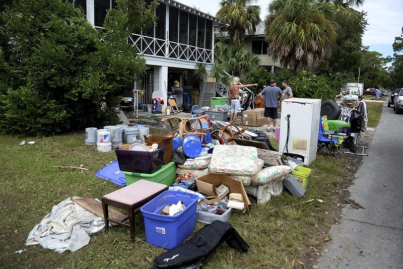 David Fettke, left, and his wife, Sonya, spend Wednesday, Sept. 13, 2017, airing out the lower level of their home on Tybee Island and putting flood-damaged items on their lawn. Storm surge flooded hundreds of homes near beaches and marshes, sunk numerous boats and trashed docks on the Georgia coast even though Irma was a weakened tropical storm when its center crossed the state more than 100 miles (160 kilometers) inland. (Dash Coleman/Savannah Morning News via AP)