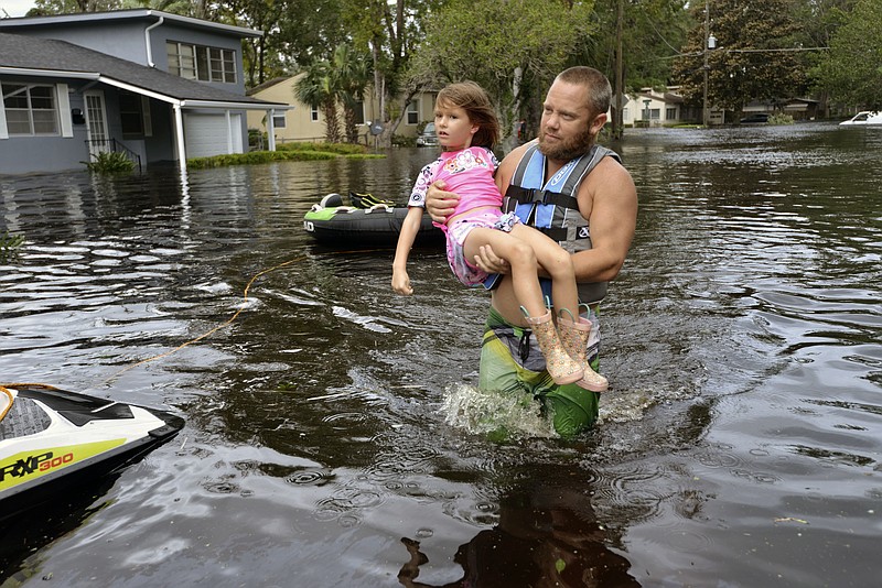 
              Tommy Nevitt carries Miranda Abbott, 6, through floodwater caused by Hurricane Irma on the west side of Jacksonville, Fla., Monday, Sept. 11 2017. (Dede Smith/The Florida Times-Union via AP)
            