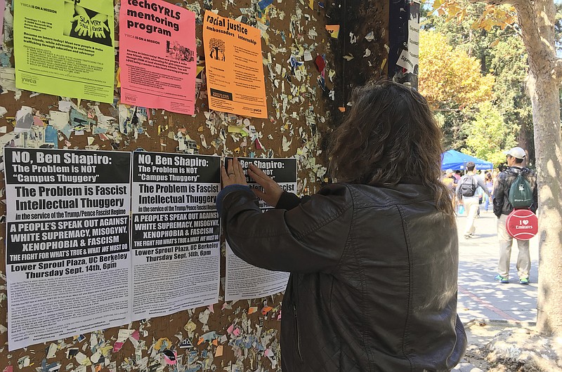 
              In this Sept. 8, 2017, photo, a woman tapes flyers on a University of California, Berkeley campus bulletin board calling for a protest against right-wing speaker Ben Shapiro in Berkeley, Calif. The university will seal off large parts of its campus like a fortress with a closed perimeter and a "very large" visible police presence Thursday, Sept. 14. City and campus authorities anticipate demonstrations at a speech by conservative commentator Ben Shapiro, a former Breitbart editor, and are preparing for possible violence with a variety of new strategies and tightened security. (AP Photo/Jocelyn Gecker)
            