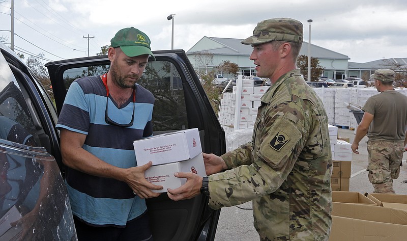 
              A member of the National Guard hands over boxes of food to Patrick Garvey in the aftermath of Hurricane Irma, Thursday, Sept. 14, 2017, in Big Pine Key, Fla. (AP Photo/Alan Diaz)
            