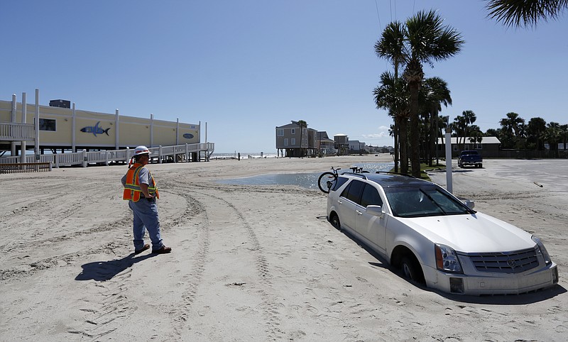 
              Greg Smith with the South Carolina Department of Transportation waits to remove a car stuck in Palmetto Blvd., in Edisto Beach, S.C., Tuesday, Sept. 12, 2017, as the road is covered in several feet of sand after Tropical Storm Irma hit. Edisto Beach suffered the same fate last year with Hurricane Matthew. (AP Photo/Mic Smith)
            