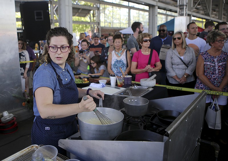 Chef Rebecca Barron, of St. John's Restaurant, stirs some grits during the Cast Iron Cook-Off at the Chattanooga Market at the First Tennessee Pavilion on Sunday, Sept. 17, in Chattanooga, Tenn. Barron was one of four local chefs competing. Each chef was given $50 to shop the market for ingredients to go with the provided red snapper. Barron won the event.