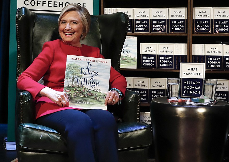 
              Hillary Clinton, holds her book "It Takes A Village" as she sits on stage at the Warner Theatre in Washington, Monday, Sept. 18, 2017, during a book tour event for her new book "What Happened" hosted by the Politics and Prose Bookstore. (AP Photo/Carolyn Kaster)
            