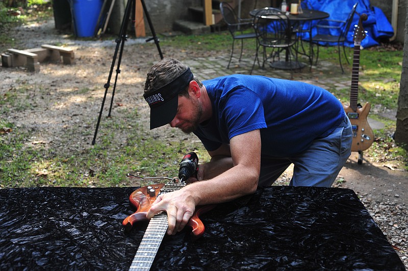 Greg Hembree said he uses no CNC or other modeling machines in creating his guitars. All the work is done completely by hand. Here, he installs a bridge onto one of his nearly finished guitars. (Contributed photo)