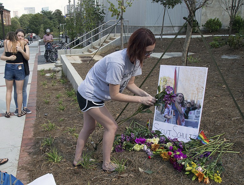 In this photo taken Sept. 17, 2017, a mourner sets out flowers at a memorial for Georgia Tech student Scout Schultz in Atlanta, Ga. Schultz was a 21-year-old who was shot and killed during a confrontation with police on campus Saturday, Sept. 16. (Steve Schaefer/Atlanta Journal-Constitution via AP)