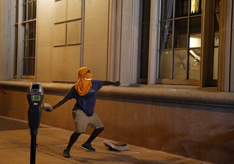 
              A man throws a rock into the window as demonstrators march in response to a not guilty verdict in the trial of former St. Louis police officer Jason Stockley, Sunday, Sept. 17, 2017, in St. Louis. Stockley was acquitted in the 2011 killing of a black man following a high-speed chase. (AP Photo/Jeff Roberson)
            