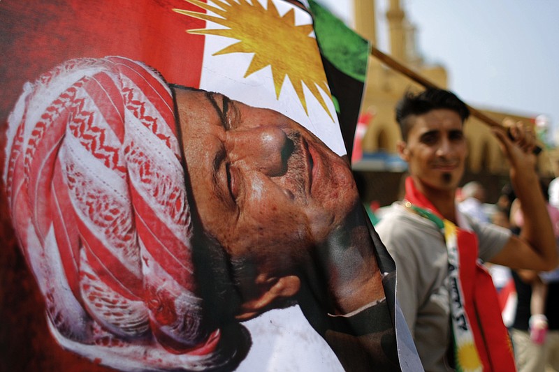
              A man holds a Kurdish flag with a picture of Iraqi Kurdish leader Masoud Barzani during a gathering to support next week's referendum in Iraq, at Martyrs Square in Downtown Beirut, Lebanon, Sunday, Sept. 17, 2017. Iraq's Kurdish region plans to hold the referendum on Sept. 25 to gauge support for independence from Iraq for the autonomous region. (AP Photo/Hassan Ammar)
            