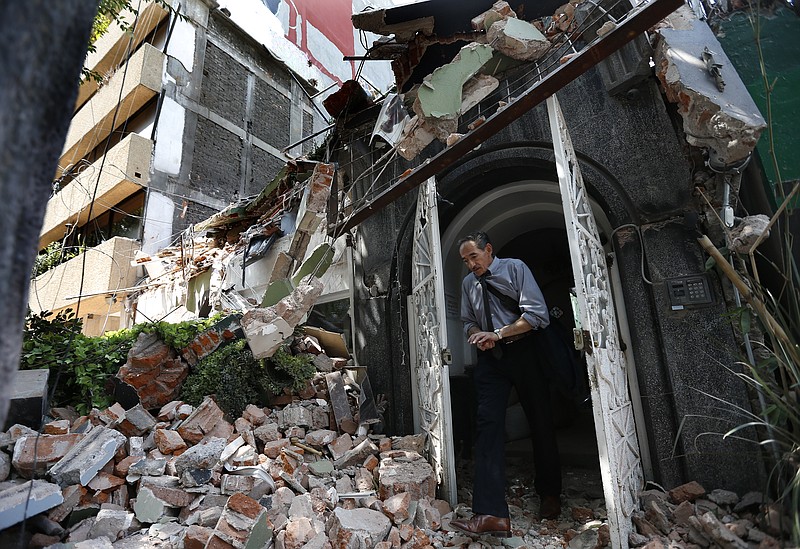 A man walks out of the door frame of a building that collapsed after an earthquake, in the Condesa neighborhood of Mexico City, Tuesday, Sept. 19, 2017. Throughout Mexico City, rescuer workers and residents dug through the rubble of collapsed buildings seeking survivors following a 7.1 magnitude quake. (AP Photo/Marco Ugarte)