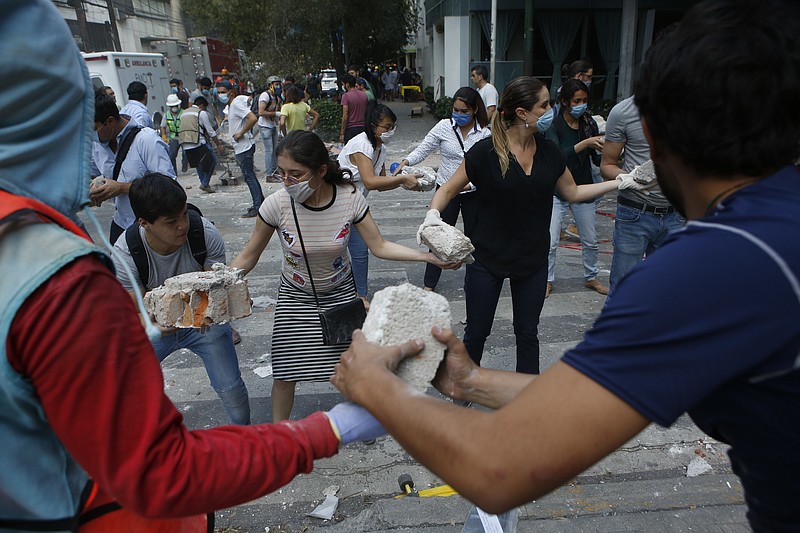 
              Volunteers pick up the rubble from a building that collapsed during an earthquake in the Condesa neighborhood of Mexico City, Tuesday, Sept. 19, 2017. A powerful earthquake jolted central Mexico on Tuesday, causing buildings to sway sickeningly in the capital on the anniversary of a 1985 quake that did major damage. (AP Photo/Rebecca Blackwell)
            