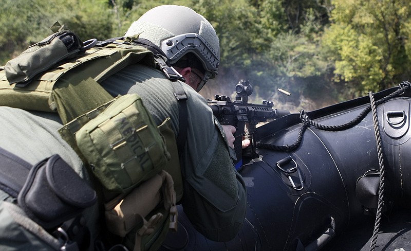 Hamilton County Sheriff's Office SWAT team member Deputy Patrick Miller fires at a target from a boat while demonstrating a waterborne assault during a media day offering hands-on experiences and demonstrations to what they do at the law enforcement firing range on Thursday, Sept. 21, in Chattanooga, Tenn.