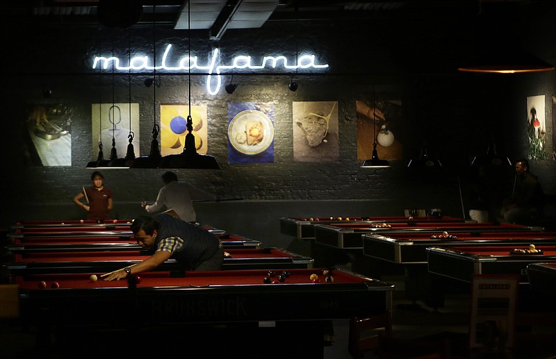 
              Locals play pool at a venue in Mexico City's La Condesa neighborhood, Friday, Sept. 22, 2017, four days after the 7.1 earthquake. The upscale Mexico City neighborhood was one of the hardest hit, with more than a half-dozen collapsed buildings in the immediate vicinity. The few Condesa residents who ventured out Friday night said they were anxious for relief from an anguishing week. (AP Photo/Nico Gonzalez)
            