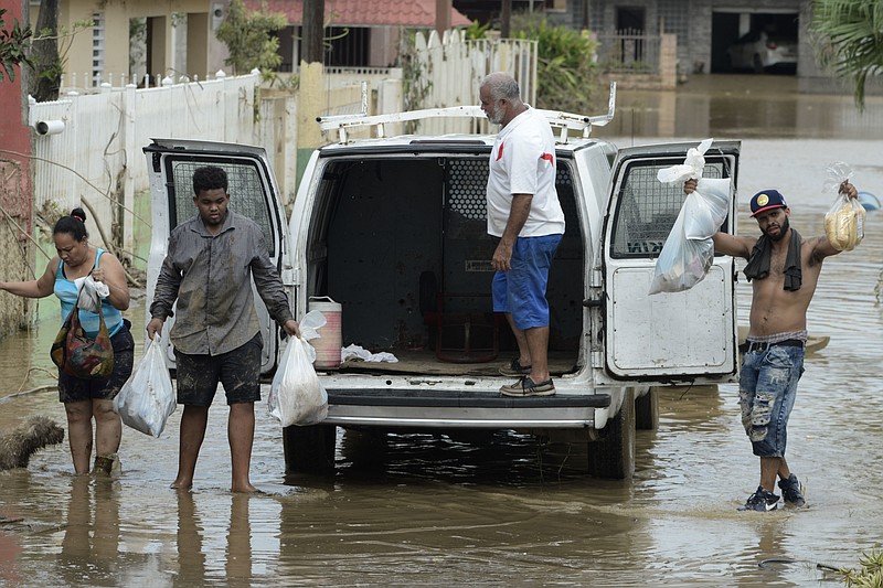 
              Residents manage provisions after the passing of Hurricane Maria, in Toa Baja, Puerto Rico, Friday, September 22, 2017. Because of the heavy rains brought by Maria, thousands of people were evacuated from Toa Baja after the municipal government opened the gates of the Rio La Plata Dam. (AP Photo/Carlos Giusti)
            