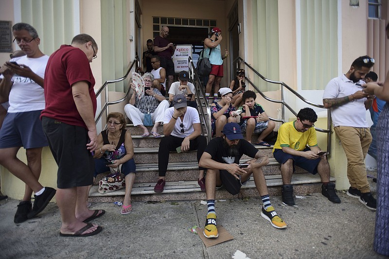 
              People congregate at a wifi hotspot in the aftermath of Hurricane Maria with many cellphone towers down in San Juan, Puerto Rico, Sunday, Sept. 24, 2017. (AP Photo/Carlos Giusti)
            