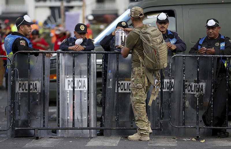 
              In this Sept. 22, 2017 photo, a civilian dressed in fatigues passes out chocolate to police guarding the site of an office building that collapsed during Tuesday's 7.1 earthquake, as search and rescue operations continue there at the corner of Oaxaca and Alvaro Obregon streets in the Roma Norte neighborhood in Mexico City. As rescue operations stretched into Day 5, residents throughout the capital have held out hope that dozens still missing might be found alive. (AP Photo/Gustavo Martinez Contreras)
            