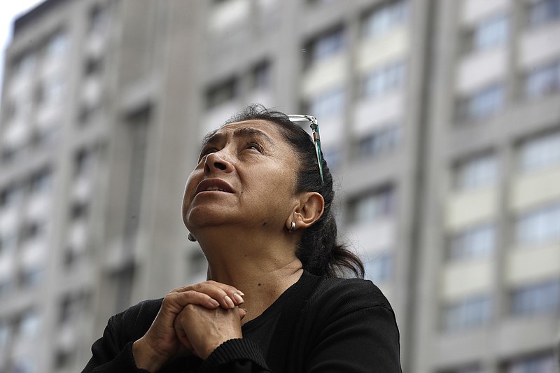 
              A woman prays during an outdoor Mass service, held outside Saint James Apostle Parish, because the church building suffered some damage during the 7.1-magnitude earthquake, in the Plaza de las Tres Culturas in Tlatelolco, Mexico City, Sunday, Sept. 24, 2017. As the search continued Sunday for survivors and the bodies of people who died in quake-collapsed buildings, specialists have fanned out to inspect buildings and determine which are unsafe after Tuesday's powerful earthquake. (AP Photo/Rebecca Blackwell)
            