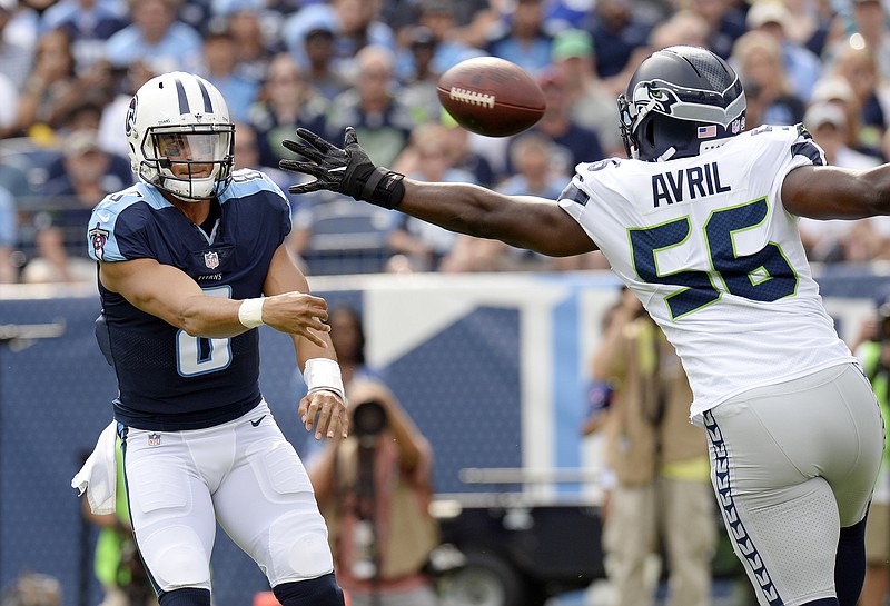 Tennessee Titans quarterback Marcus Mariota (8) passes past Seattle Seahawks defensive end Cliff Avril (56) in the first half of an NFL football game, Sunday, Sept. 24, 2017, in Nashville, Tenn. (AP Photo/Mark Zaleski)