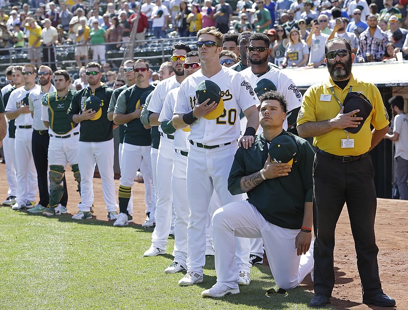 
              Oakland Athletics' Mark Canha (20) places his hand on the shoulder of Bruce Maxwell as Maxwell takes a knee during the national anthem prior to a baseball game against the Texas Rangers, Sunday, Sept. 24, 2017, in Oakland, Calif. (AP Photo/Ben Margot)
            