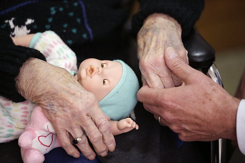 
              FILE - In this April 14, 2016, file photo, a son, at right, holds his mother's hand as they talk at her nursing home in Adrian, Mich. Long-term care costs are still rising and the most expensive option, a private nursing home room, may soon top $100,000 per year. (AP Photo/Carlos Osorio, File)
            