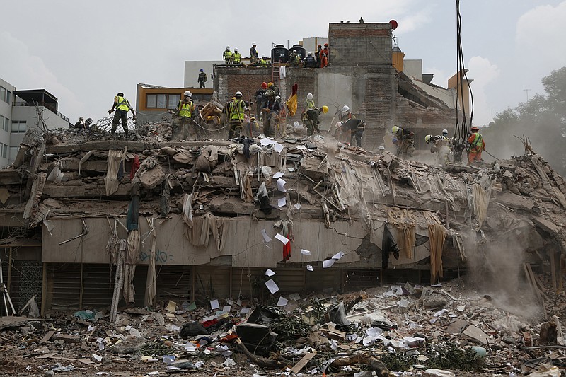 Workers shovel papers and debris off the top of the rubble of a building that collapsed in last week's 7.1 magnitude earthquake, at the corner of Gabriel Mancera and Escocia streets in the Del Valle neighborhood of Mexico City, Monday, Sept. 25, 2017. Search teams were still digging through dangerous piles of rubble Monday, hoping against the odds to find survivors after the Sept. 19 quake.(AP Photo/Rebecca Blackwell)