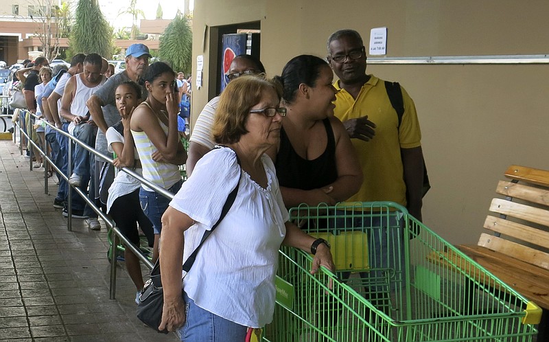 
              People wait in line outside a grocery store to buy food that wouldn't spoil and that they could prepare without electricity, in San Juan, Monday, Sept. 25, 2017. Most stores and restaurants remained closed Monday. Nearly all of Puerto Rico was without power or water five days after Hurricane Maria.(AP Photo/Ben Fox)
            