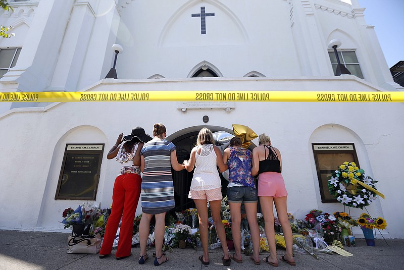 FILE - In this June 18, 2015, file photo, a group of women pray together at a makeshift memorial on the sidewalk in front of the Emanuel AME Church, in Charleston, S.C. Dylann Roof, shot a killed nine people while they were in a bible study at the church. A shooting at a Tennessee church on Sunday, Sept. 24, 2017, has demonstrated again that deadly violence at U.S. houses of worship is not rare. (AP Photo/Stephen B. Morton, File)
