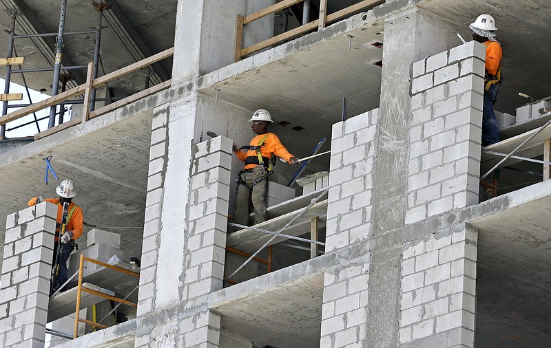 In this Thursday, May 4, 2017, photo, construction workers work on an apartment high rise in Miami. On Thursday, Sept. 28, 2017, the Commerce Department issues the third and final estimate of how the U.S. economy performed in the April-June quarter. (AP Photo/Alan Diaz)