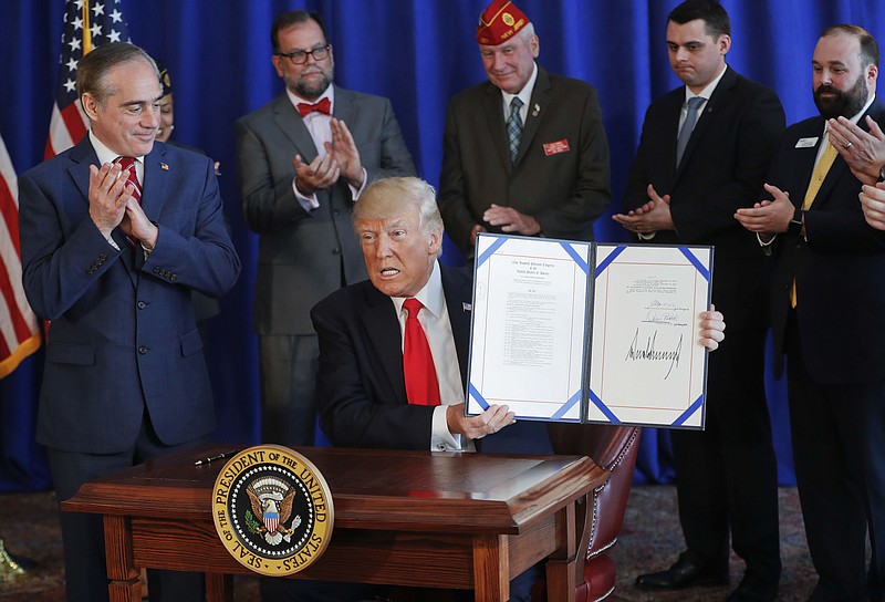 
              FILE - In this Saturday, Aug. 12, 2017 file photo, President Donald Trump holds the Veteran's Affairs Choice and Quality Employment Act of 2017 after signing it at Trump National Golf Club in Bedminister, N.J. Standing with Trump is Veterans Affairs Secretary David Shulkin, left. Weeks after receiving emergency aid in August 2017, the Department of Veterans Affairs is cautioning that the private-sector health program backed by Trump could run low again on money sooner than expected, threatening to disrupt care for hundreds of thousands of veterans in two months. (AP Photo/Pablo Martinez Monsivais)
            