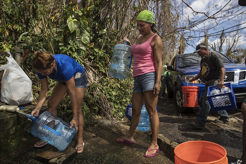 Luz Rosado, center, directs the filling of water vessels at a natural spring at her home in Toa Alta, Puerto Rico, earlier this week.. The Trump administration, which has insisted that its efforts in Puerto Rico were adequate, faces increasing pressure to mount a more aggressive response to Hurricane Maria's devastating lashing of the island. (Victor J. Blue/The New York Times)
