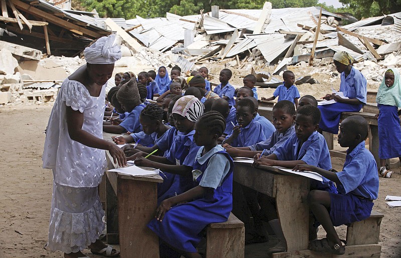 
              FILE- In this Tuesday, Aug. 4, 2009 file photo, a teacher and owner of the Goodness Mercy school Julliana Aunie, left, seen with her pupils sitting in front of their school, that was destroyed during a wave of violence, in Maiduguri, Nigeria. Boko Haram's ongoing insurgency in northern Nigeria has forced the closure of more than 57 percent of schools in Borno state, leaving about 3 million children without an education as the school year begins, the United Nations Children's Fund said Friday, Sept. 29, 2017. (AP Photo/Sunday Alamba File)
            