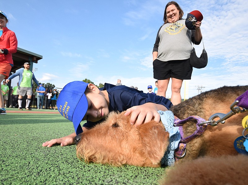 Jackson Hardin, 7, gives some love to Raleigh, an Airedale Terrier, on the turf at Warner Park before the start of the inaugural Miracle League ball game. Hardin's mother, Amanda Hardin, looks on. Raleigh is a service dog owned by Lynne Dorsey, of Blue Cross Blue Shield.