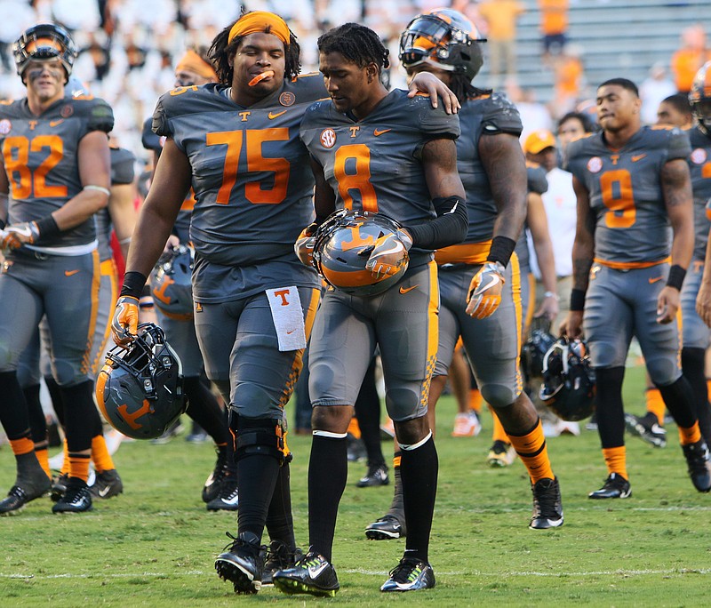 Tennessee football players Jashon Robertson (75) and Justin Martin (8) walk off the field together after the Vols' 41-0 loss to Georgia on Saturday in Neyland Stadium.