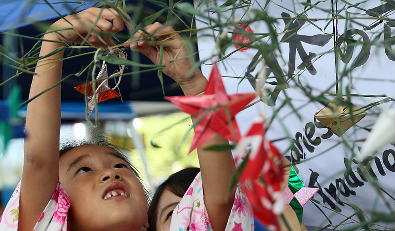 Iroha Yagi, 6, puts a Japanese ninja star onto a tree Sunday, Oct. 1, 2017, during the Chattanooga Market's CultureFest in Chattanooga, Tenn. The event was host to a multicultural fashion show, dance performances and culturally-themed art.