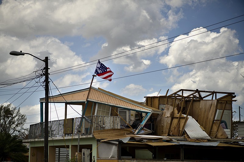 
              A political party banner waves over a home damaged in the passing of Hurricane Maria, in the community of Ingenio in Toa Baja, Puerto Rico, Monday, Oct. 2, 2017. President Donald Trump is planning to visit the U.S. territory on Tuesday. (AP Photo/Ramon Espinosa)
            